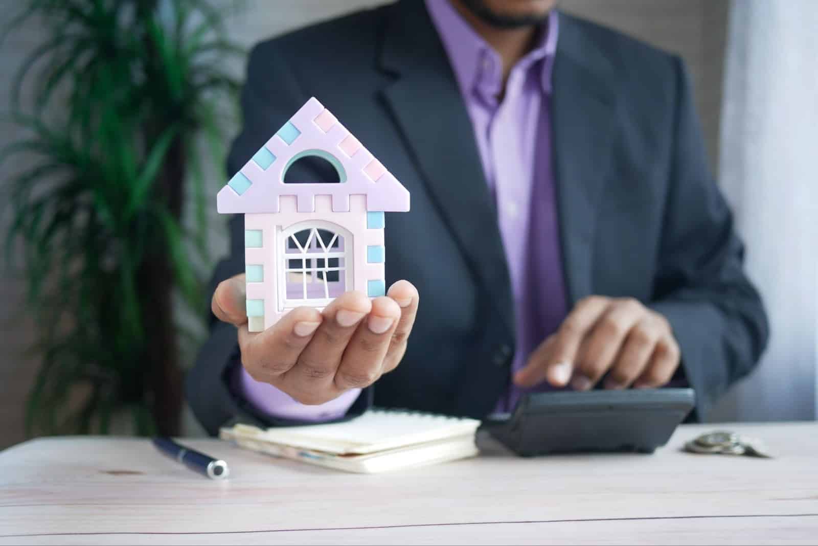 homme tenant une maison illustrant un modèle d'offre d'achat immobilier